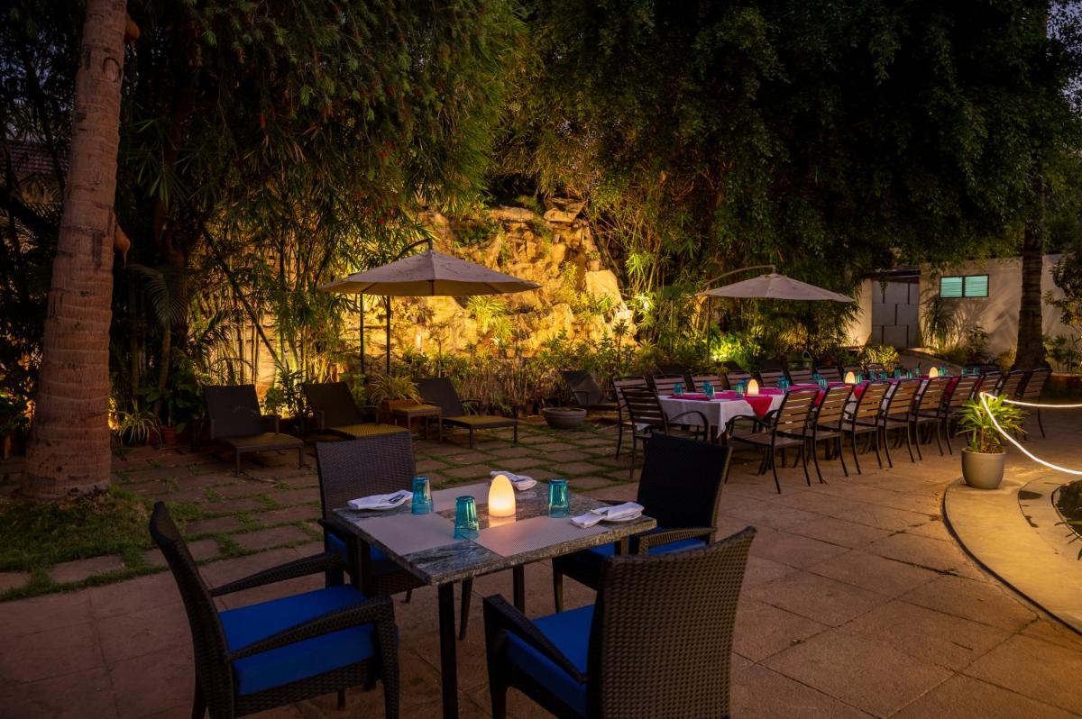 a restaurant with tables and chairs and umbrellas at night at Southern Star,Mysore in Mysore