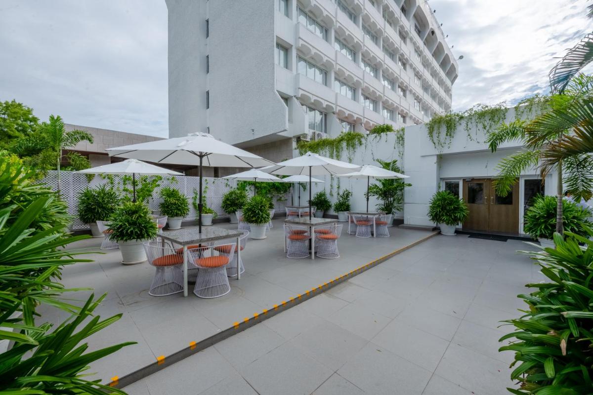 a courtyard with tables and umbrellas in a building at Southern Star,Mysore in Mysore