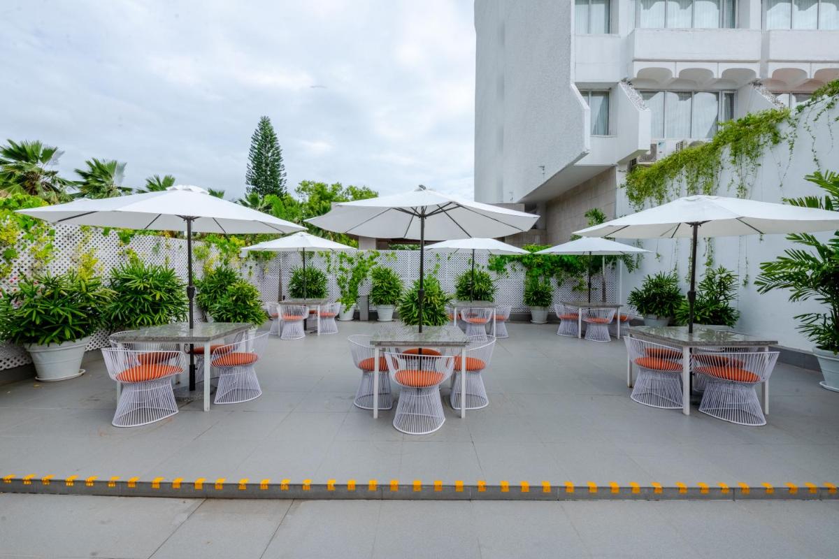 a patio with tables and chairs with umbrellas at Southern Star,Mysore in Mysore