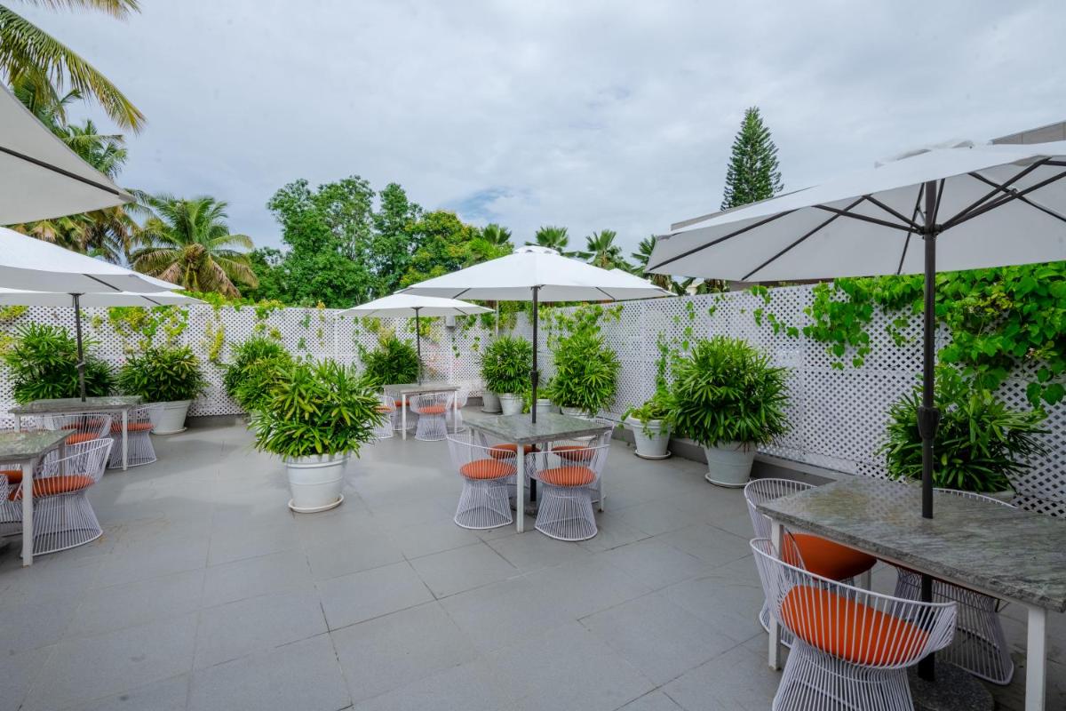 a patio with tables and chairs and umbrellas at Southern Star,Mysore in Mysore