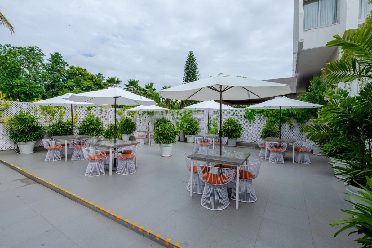 an outdoor patio with tables and chairs and umbrellas at Southern Star,Mysore in Mysore