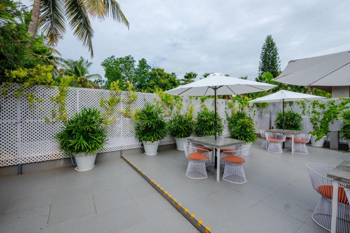 a patio with tables and chairs with plants and umbrellas at Southern Star,Mysore in Mysore