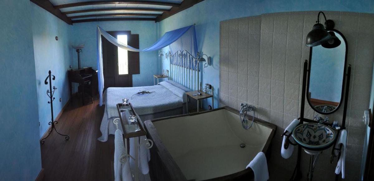 Un baño con bañera y una cama en una habitación. en Hotel Rural y SPA Kinedomus Bienestar, en Aranda de Duero