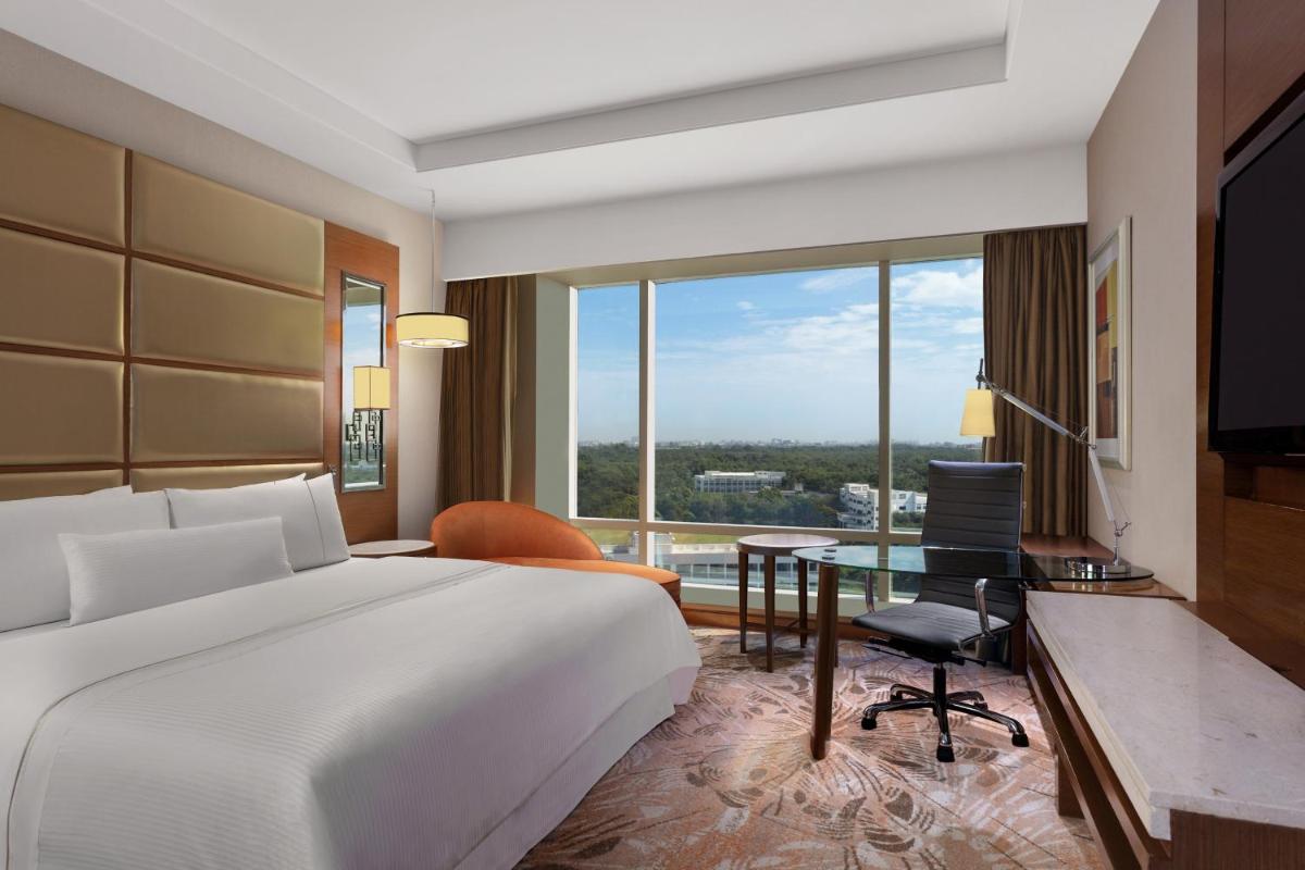 a hotel room with a bed and a desk and a window at The Westin Chennai Velachery in Chennai