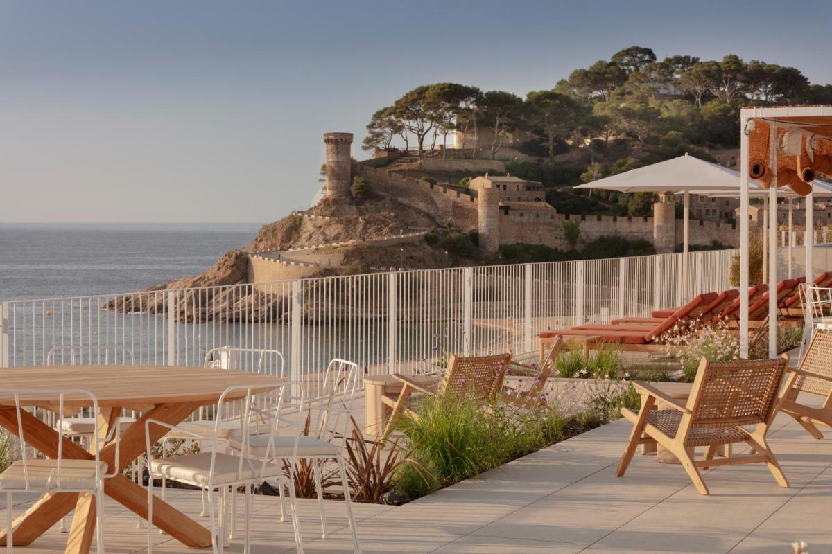 Un patio con mesa y sillas y el mar. en Elisabeth by the Sea Hotel, en Tossa de Mar