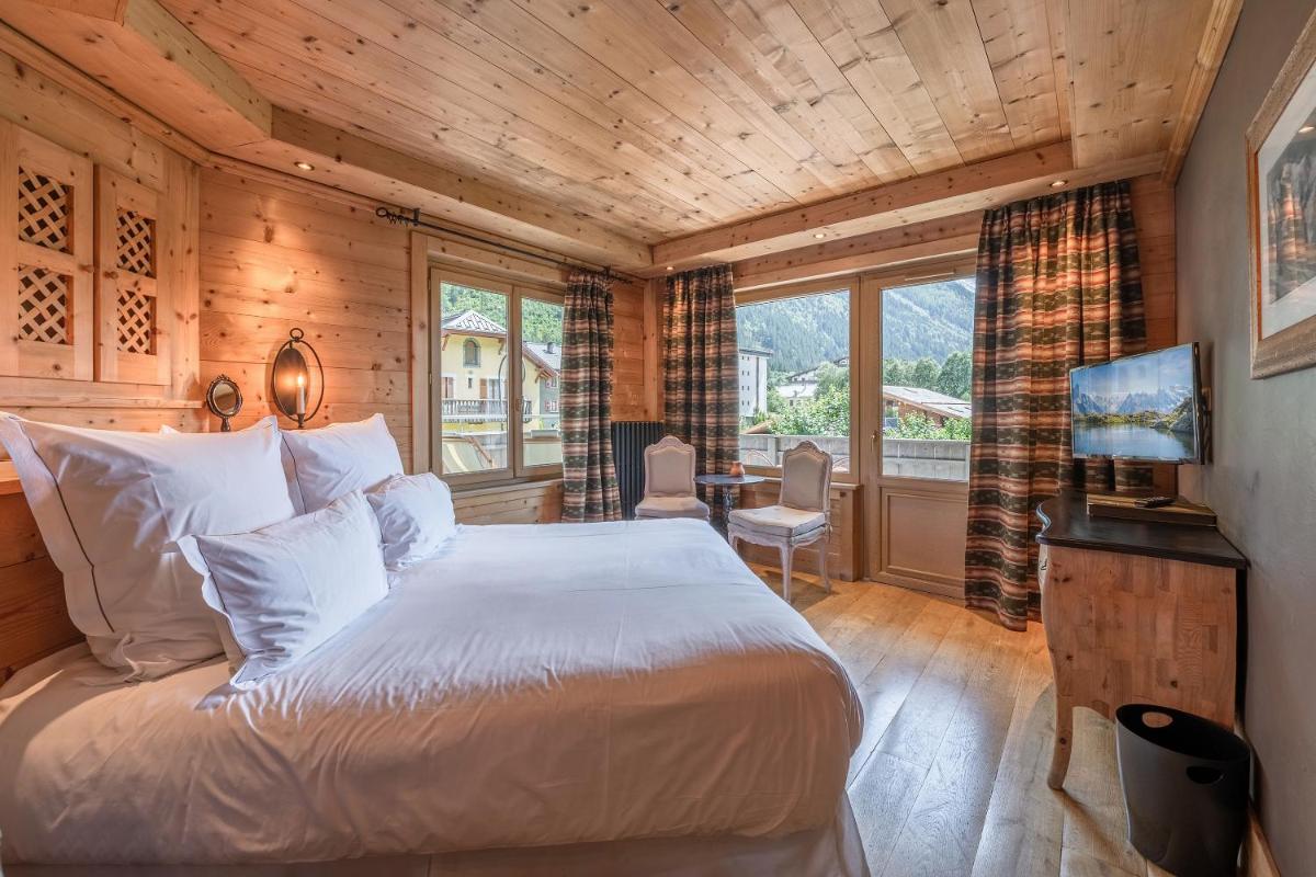 une chambre avec un grand lit dans une pièce aux murs en bois dans l'établissement Chalet-Hôtel Hermitage, à Chamonix-Mont-Blanc