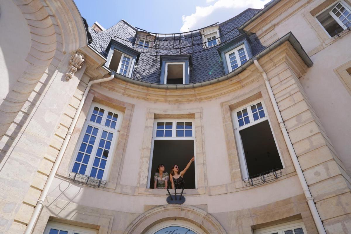 2 personnes dans une fenêtre d'un bâtiment dans l'établissement Hôtel Littéraire Stendhal et Spa, à Nancy