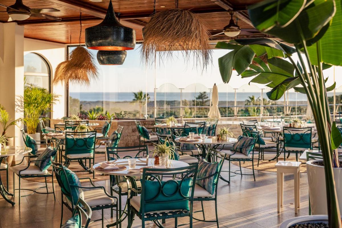um restaurante com mesas, cadeiras e plantas em Hotel Quinta do Lago na Quinta do Lago