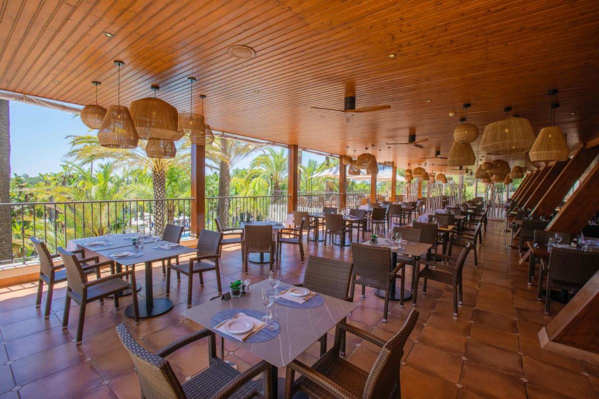 uma sala de jantar com mesas, cadeiras e janelas em Ria Park Hotel & Spa no Vale do Lobo