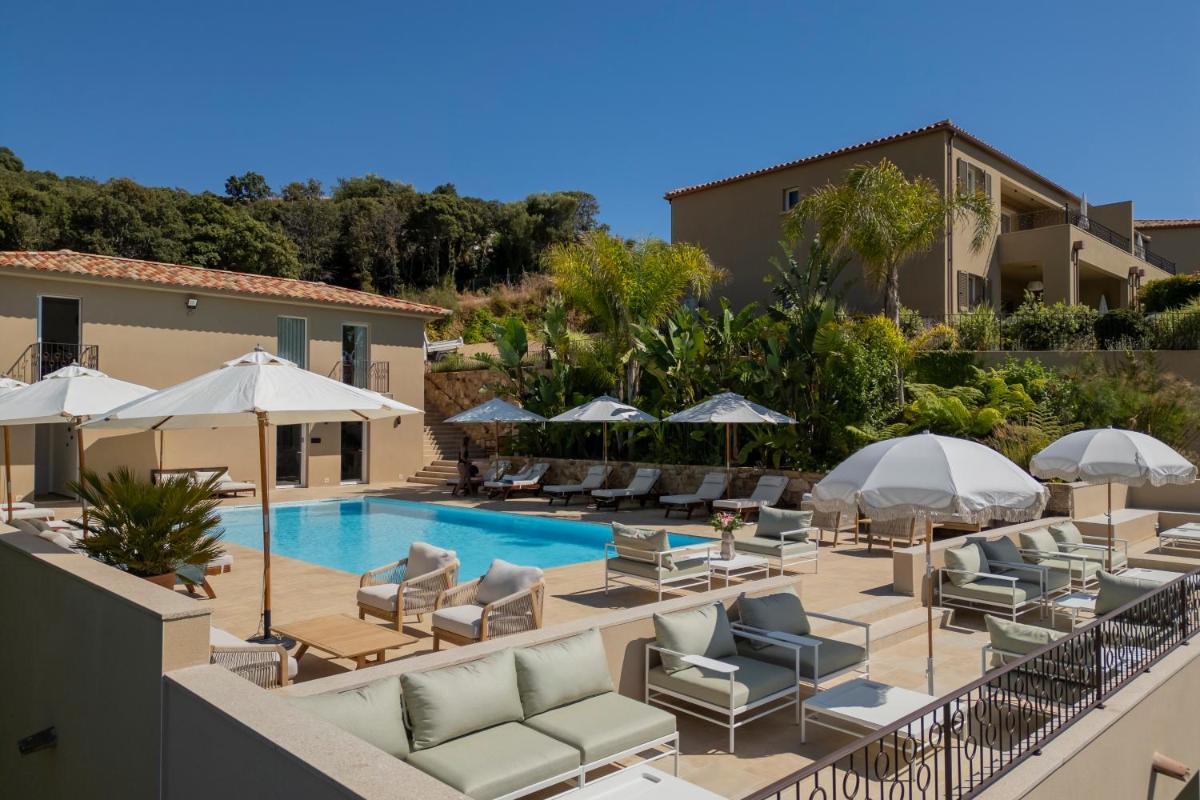 un complexe avec une piscine, des chaises longues et des parasols dans l'établissement Résidence Omigna, à Cargèse
