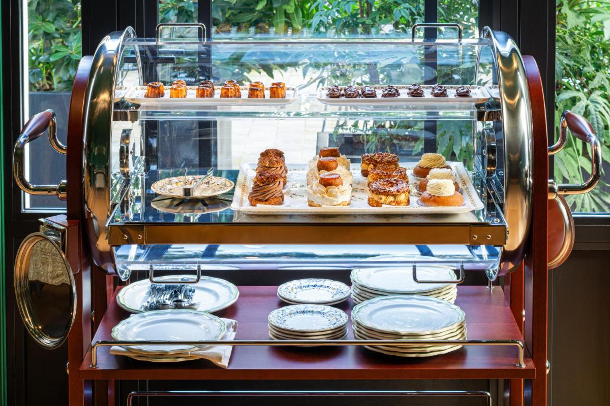 une vitrine avec des pâtisseries et des assiettes sur une table dans l'établissement Hôtel & SPA Napoléon, à Fontainebleau