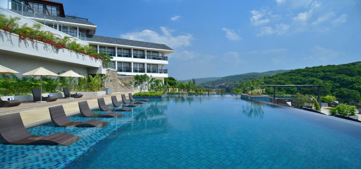 a swimming pool with chairs and a hotel at Courtyard by Marriott Mahabaleshwar in Mahabaleshwar