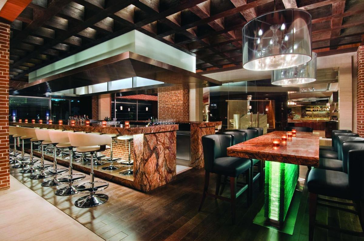 a bar with leather chairs and a wooden counter at Hyatt Regency Chennai in Chennai