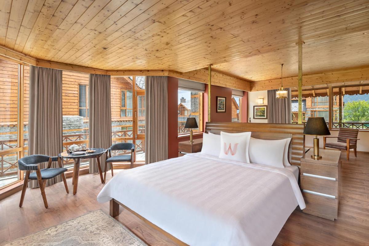 a bedroom with a bed and a table and chairs at Welcomhotel By ITC Hotels, Hamsa Manali in Manāli a bedroom with a bed and a table and chairs at Welcomhotel By ITC Hotels, Hamsa Manali in Manāli