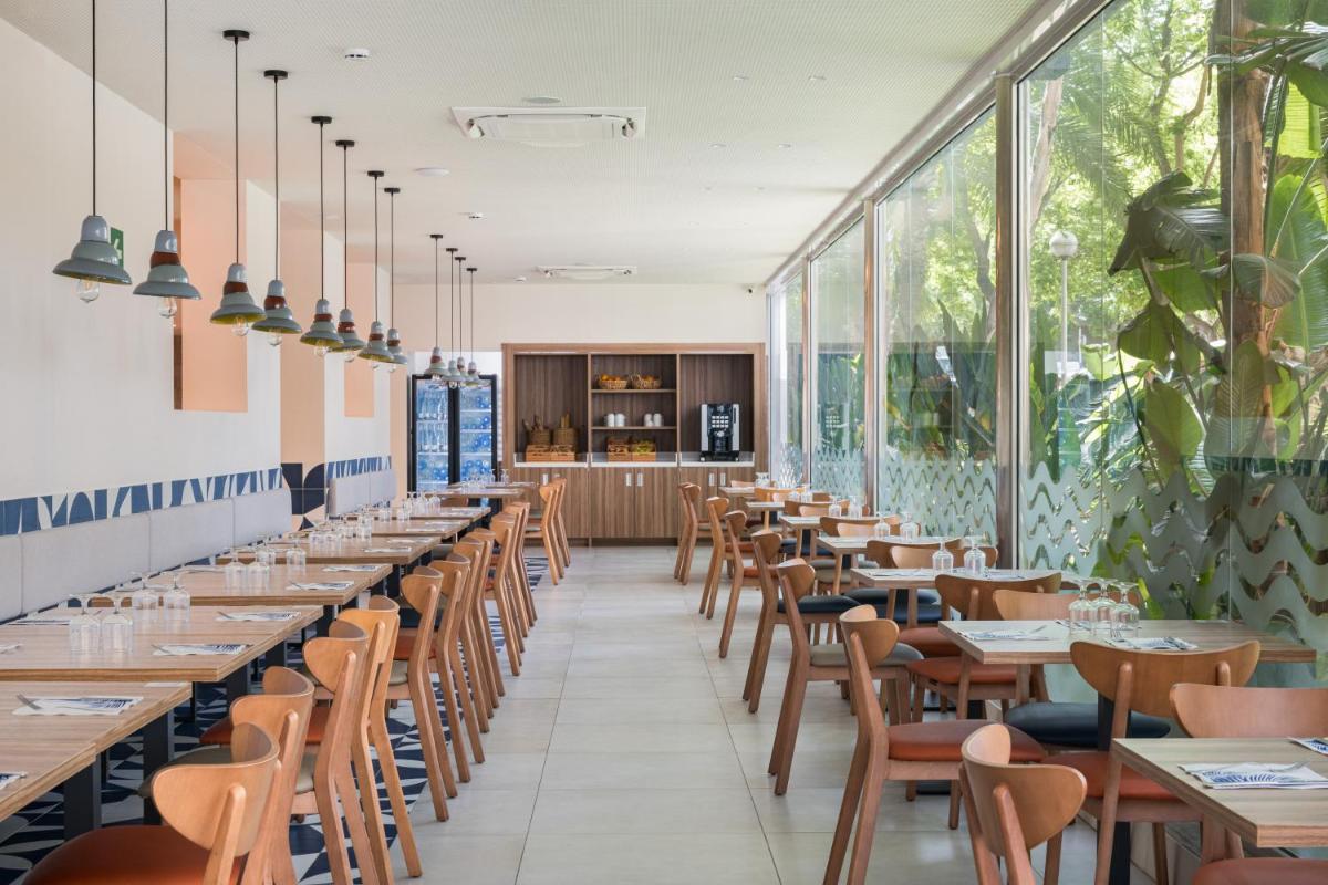 una fila de mesas y sillas en un restaurante con ventanas en Eurosalou & Spa, en Salou