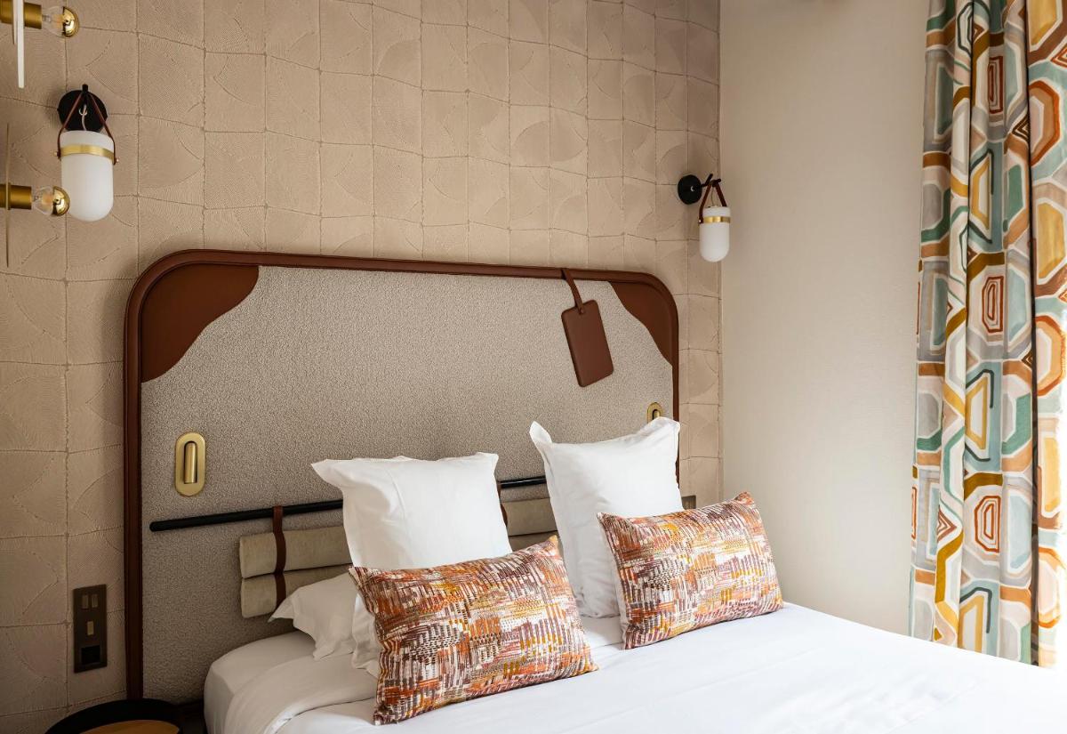 une chambre avec un lit avec des draps blancs et des oreillers dans l'établissement Hôtel Hiro Paris, à Paris