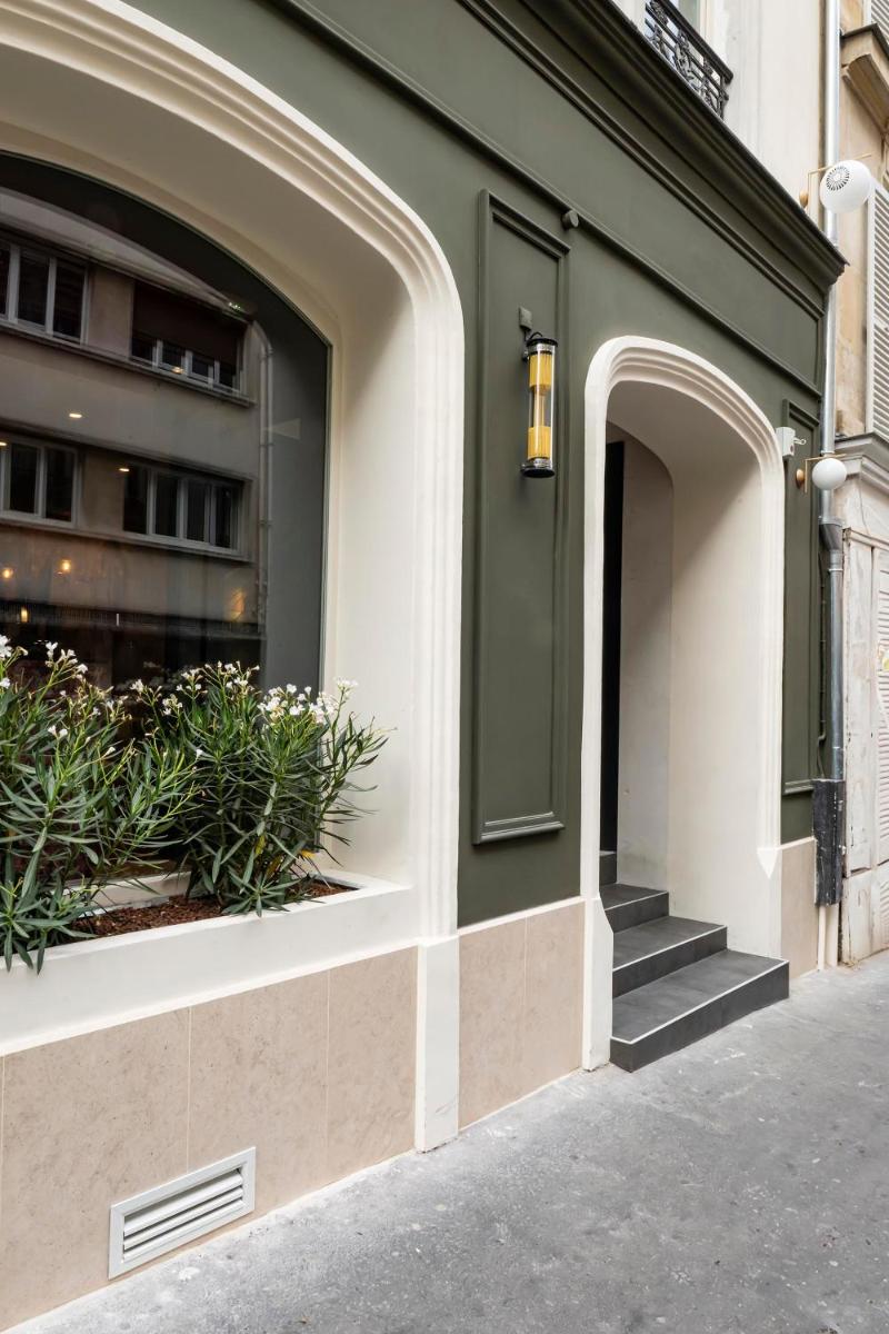un bâtiment avec une porte verte et quelques plantes dans l'établissement Hôtel Hiro Paris, à Paris