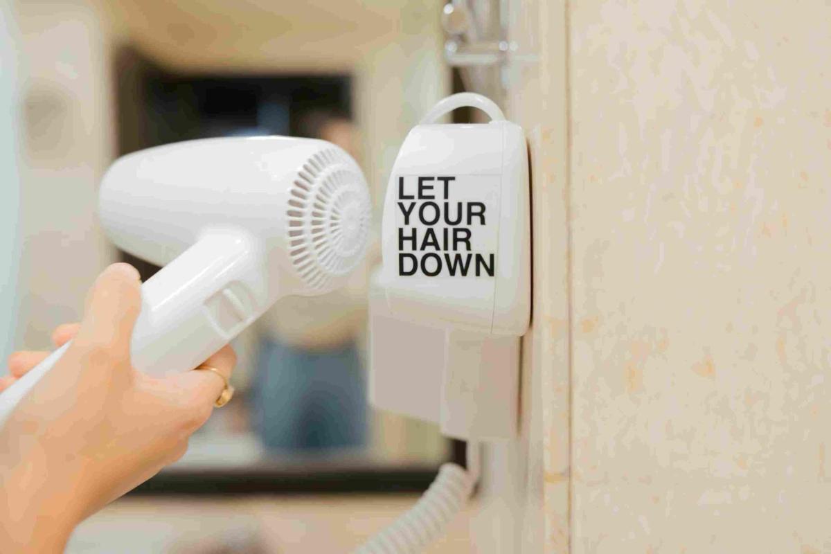 a person holding a blow dryer on a door at Sunday Hotel Jaipur in Jaipur