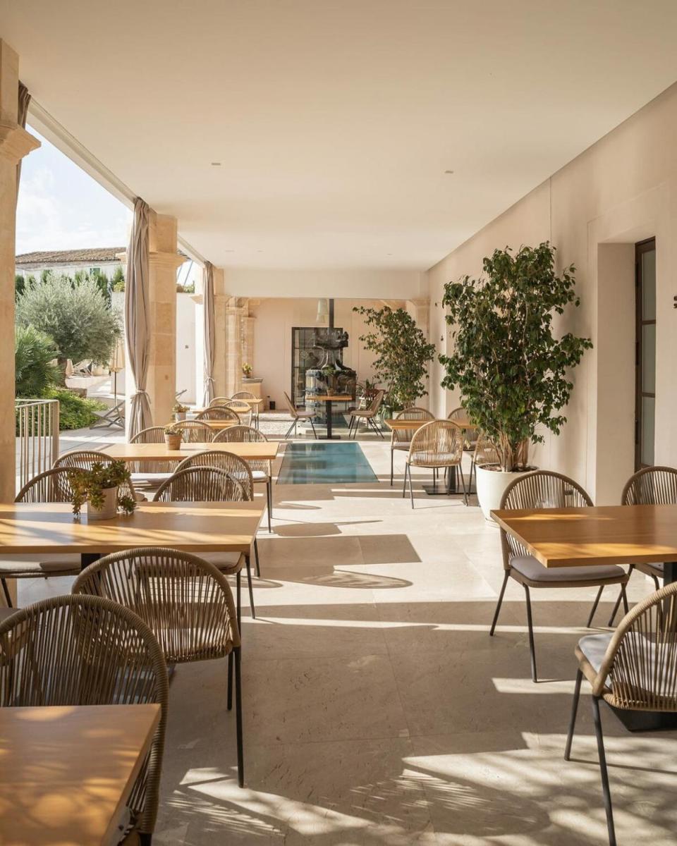 Un restaurante con mesas y sillas y una piscina. en Ynaira hotel & Spa, en Ariany