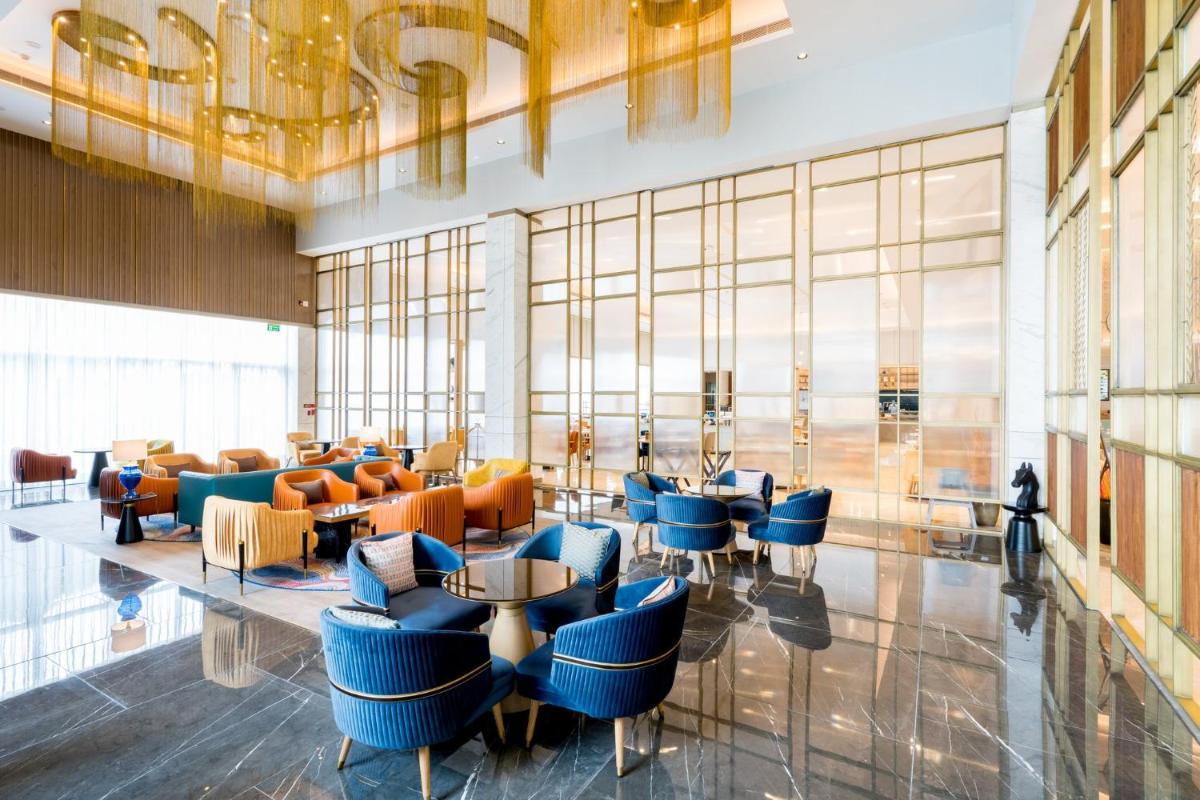a lobby of a hotel with blue chairs and tables at Holiday Inn Lucknow Airport by IHG in Lucknow