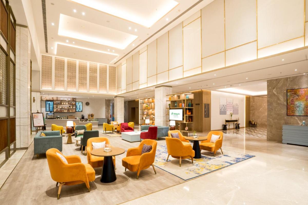 a lobby with couches tables and chairs at Holiday Inn Lucknow Airport by IHG in Lucknow