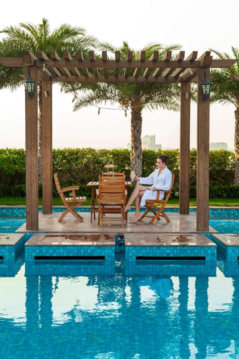 a woman sitting in a chair next to a swimming pool at Seven Seas Hotel in New Delhi
