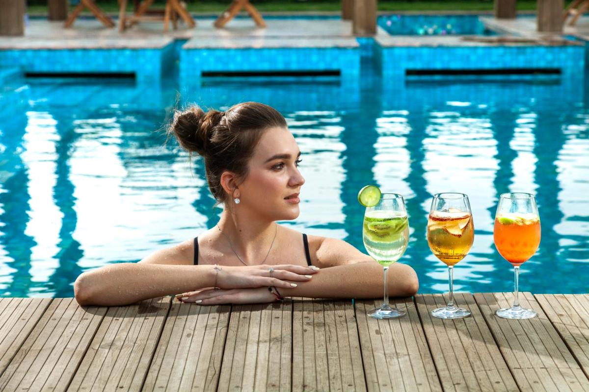a woman sitting on a dock with two glasses of wine at Seven Seas Hotel in New Delhi