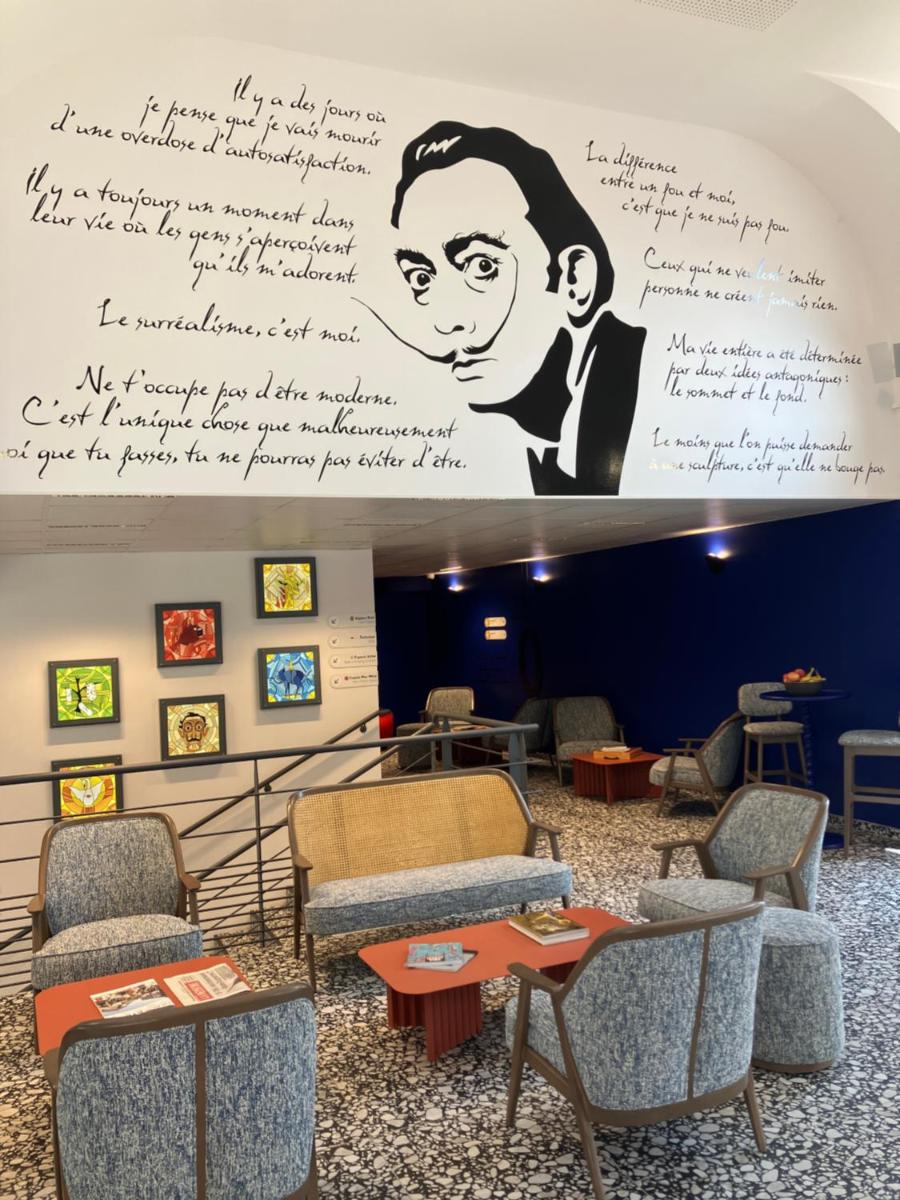 une salle d'attente avec des chaises et un mur avec un dessin de femme dans l'établissement Dali Hôtel Montauban, à Montauban