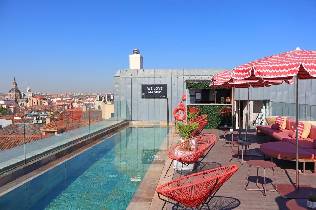 Una piscina con sillas y mesas en un edificio. en Pestana Collection Plaza Mayor, en Madrid