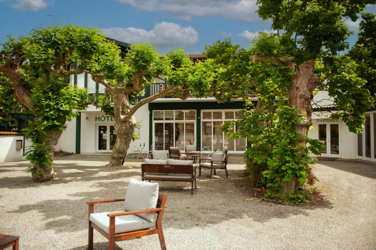 une terrasse avec des chaises et des tables devant un bâtiment dans l'établissement Logis Thermal, à Saubusse