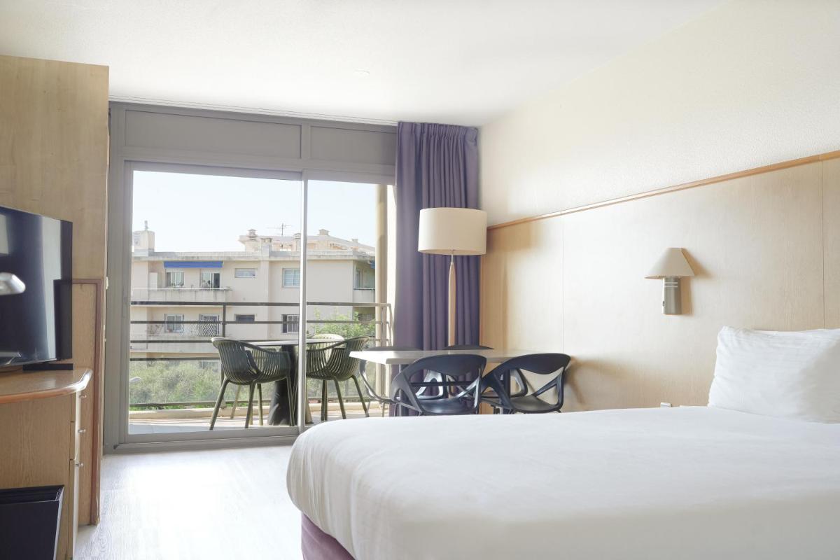 Cette chambre dispose d'un lit et d'un balcon avec une table. dans l'établissement Thalazur Antibes - Résidence & Spa, à Antibes