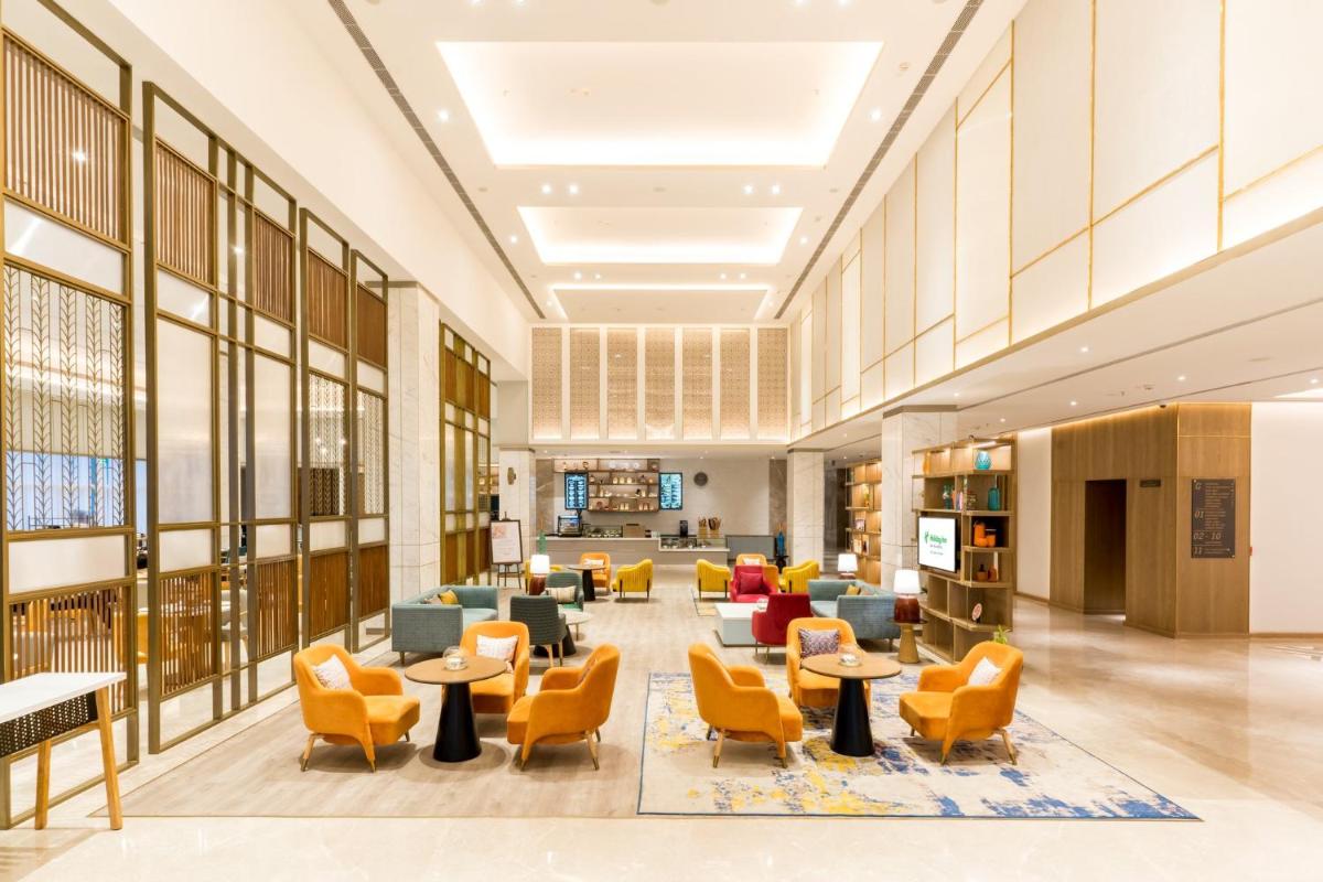 a lobby of a library with chairs and tables at Holiday Inn Lucknow Airport by IHG in Lucknow