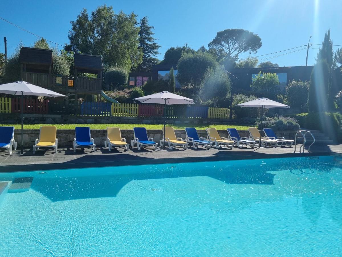 um grupo de cadeiras e guarda-sóis ao lado de uma piscina em Prazer da Natureza Resort & Spa em Caminha