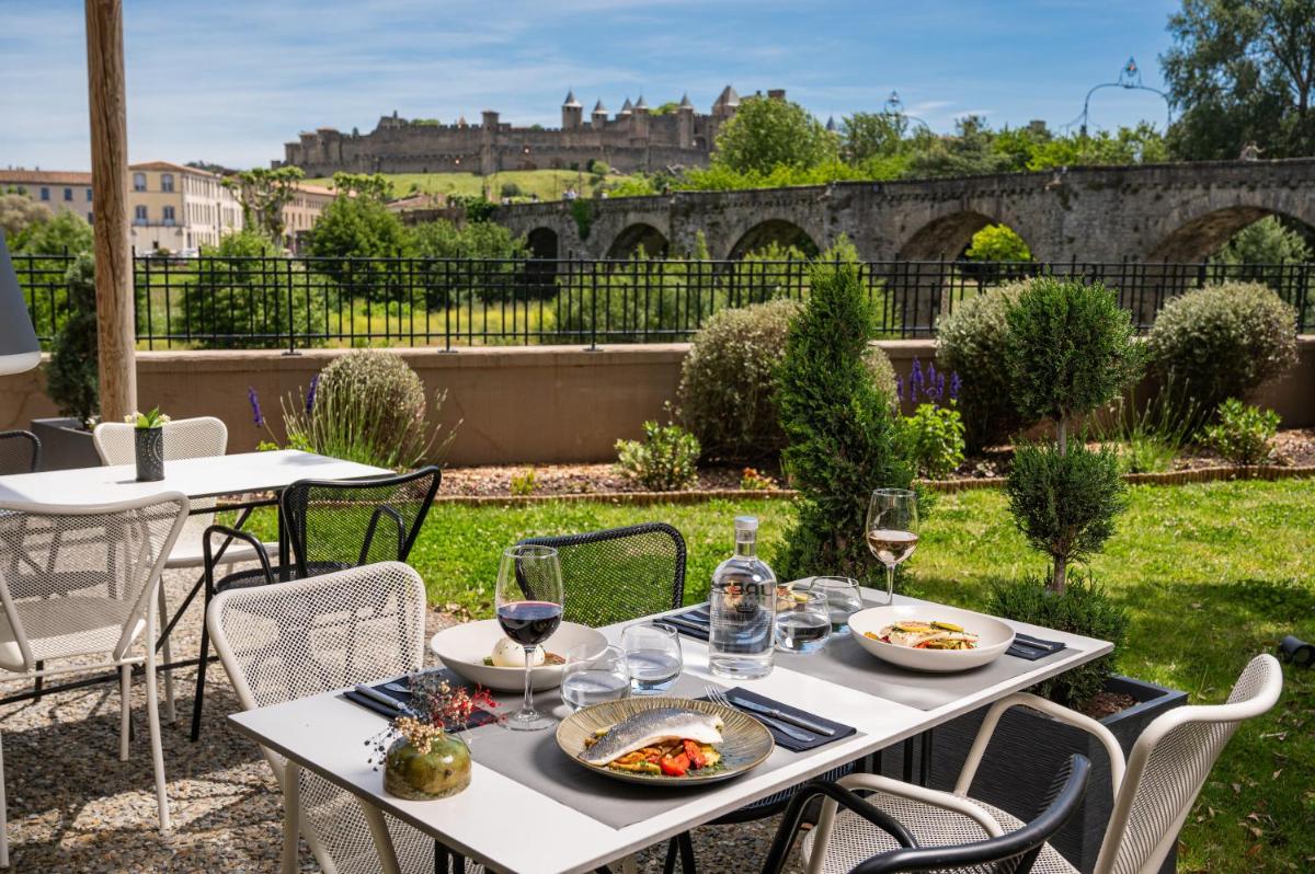 une table avec des assiettes de nourriture et des verres de vin dans l'établissement Hotel du Roi & Spa by SOWELL COLLECTION, à Carcassonne