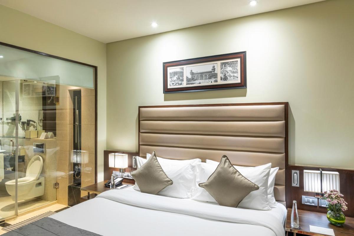 a bedroom with a bed and a glass shower at Vivanta Hyderabad, Begumpet in Hyderabad a bedroom with a bed and a glass shower at Vivanta Hyderabad, Begumpet in Hyderabad