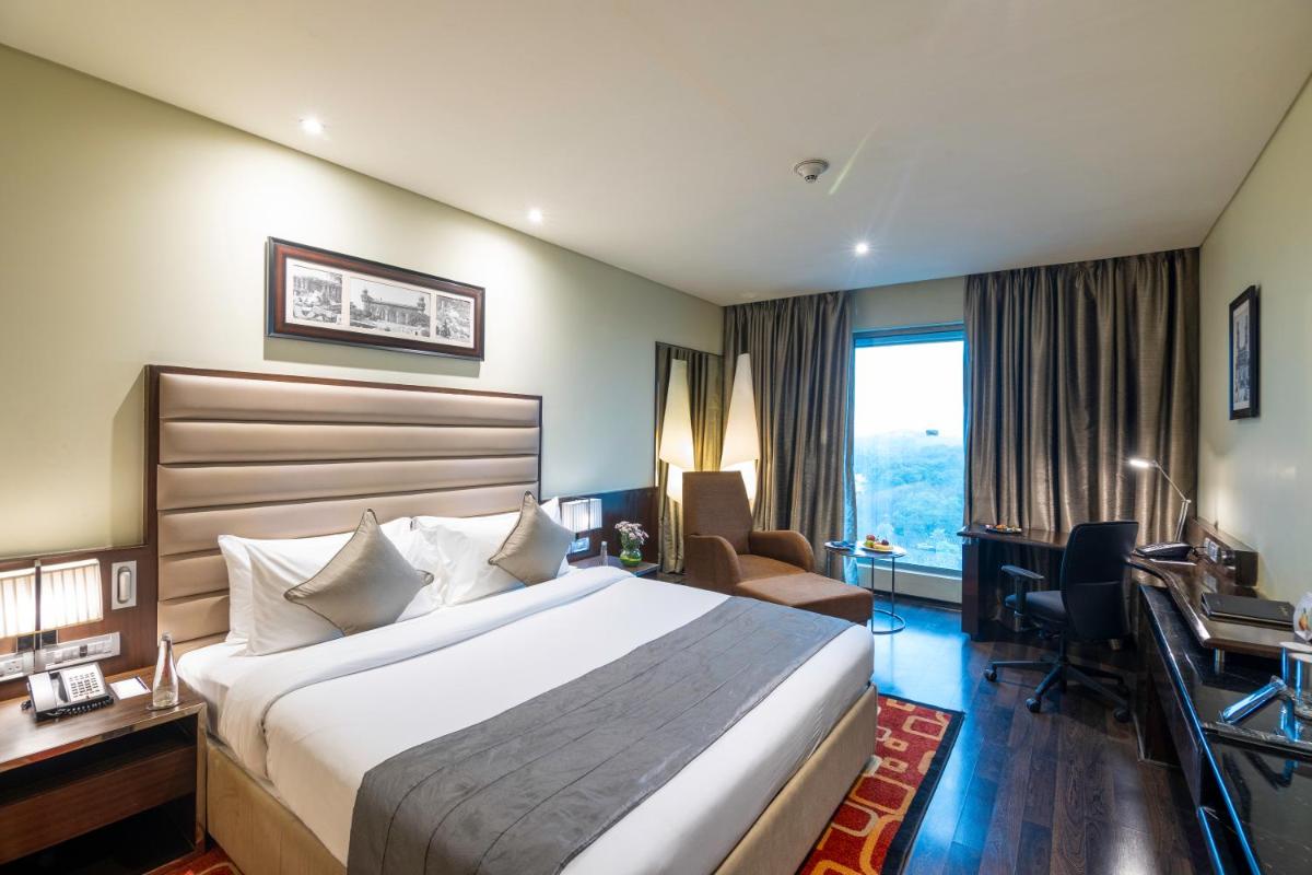 a hotel room with a large bed and a desk at Vivanta Hyderabad, Begumpet in Hyderabad a hotel room with a large bed and a desk at Vivanta Hyderabad, Begumpet in Hyderabad