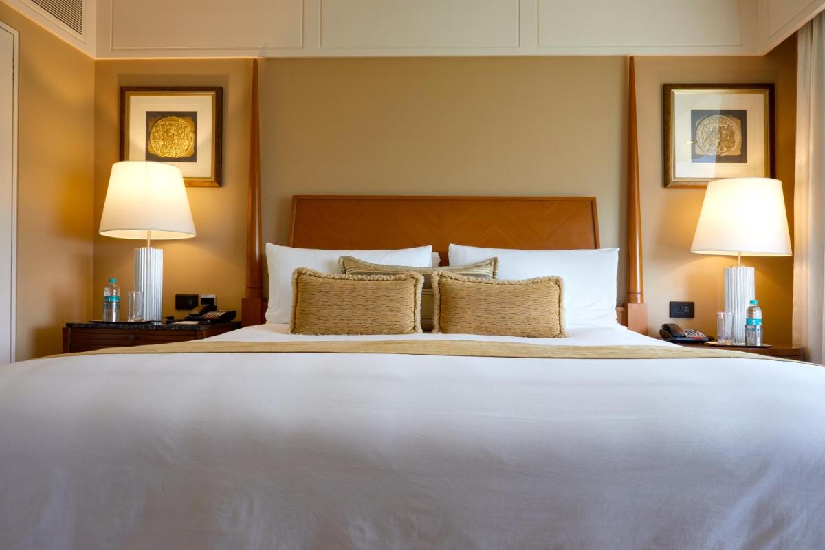a bedroom with a large white bed with two lamps at The Leela Mumbai in Mumbai a bedroom with a large white bed with two lamps at The Leela Mumbai in Mumbai