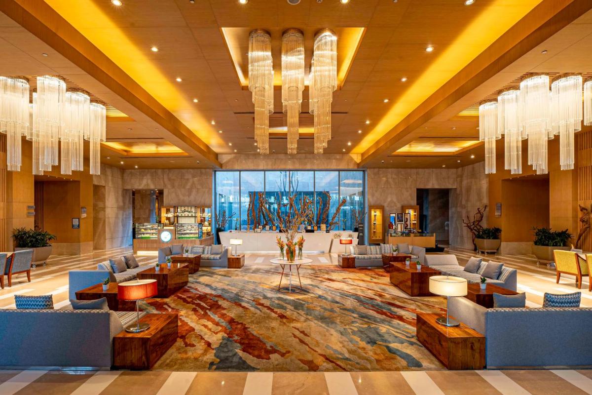 a hotel lobby with couches and tables and chandeliers at Radisson Blu Hotel Amritsar in Amritsar