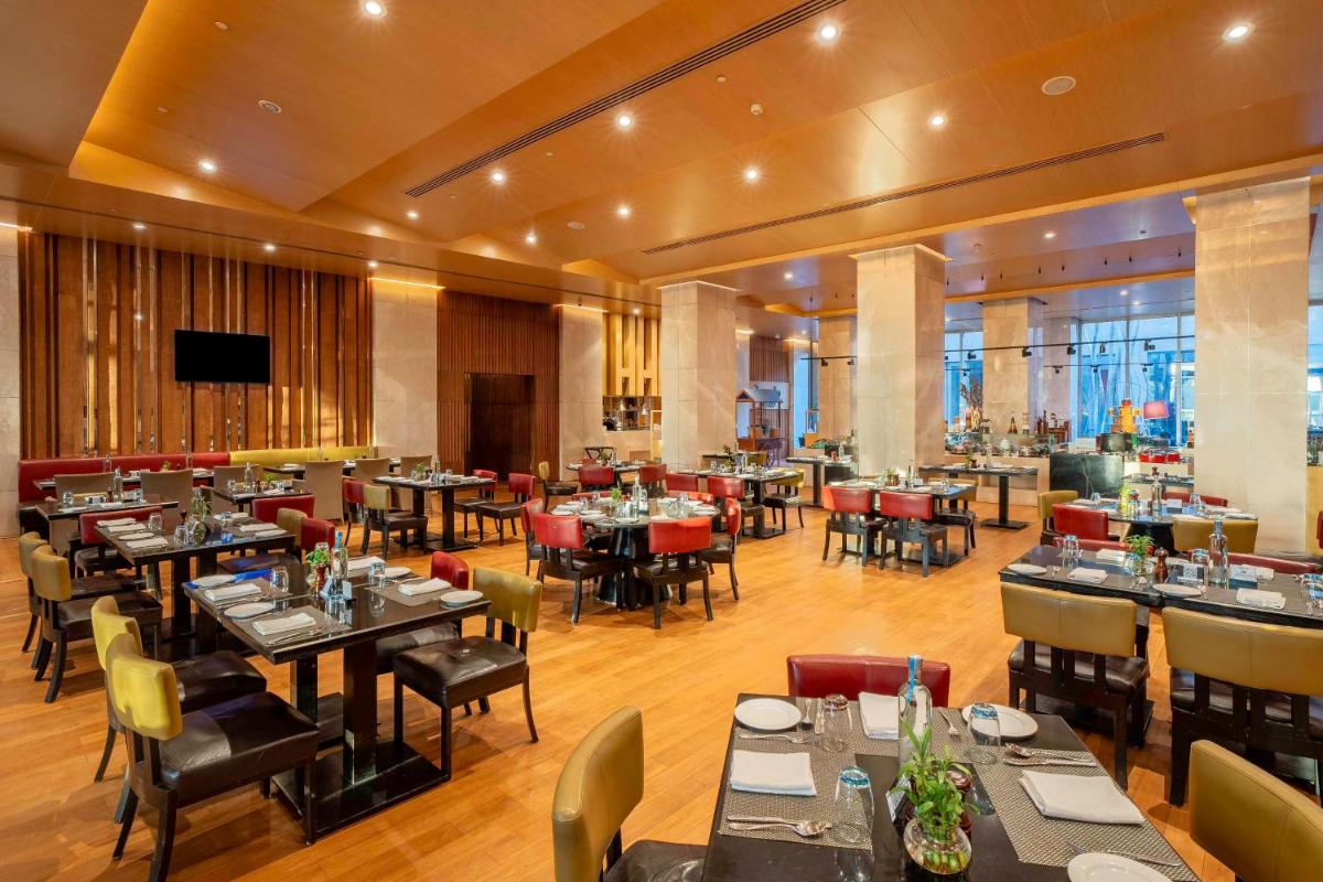 a dining room with tables and chairs in a restaurant at Radisson Blu Hotel Amritsar in Amritsar