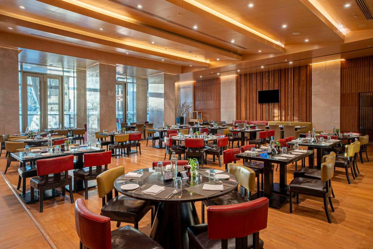 a restaurant with tables and chairs and a television at Radisson Blu Hotel Amritsar in Amritsar