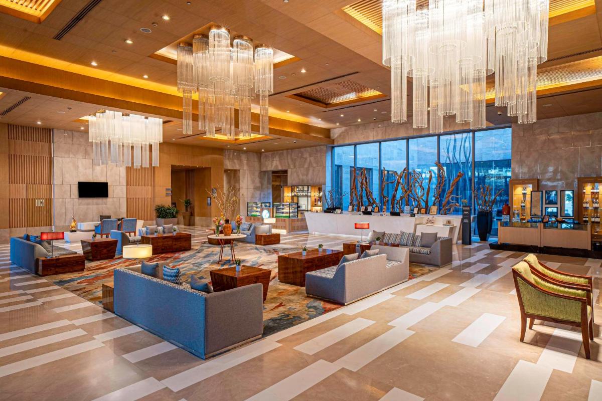a lobby of a hotel with couches and chandeliers at Radisson Blu Hotel Amritsar in Amritsar