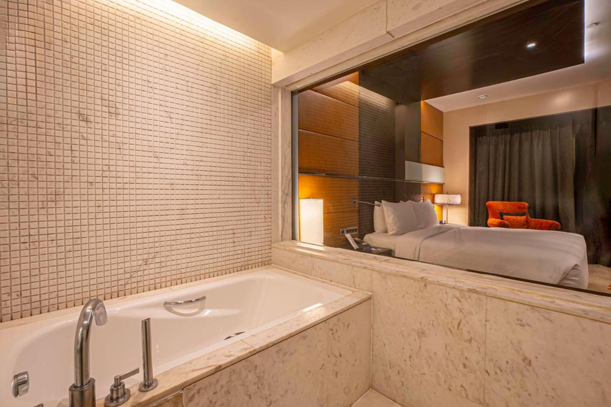a bathroom with a tub and a bedroom with a bed at Radisson Blu Hotel Amritsar in Amritsar