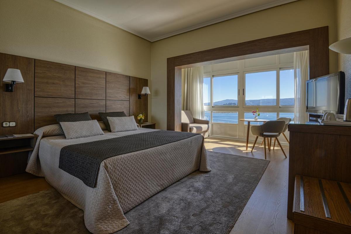 Un dormitorio con una cama grande y una ventana grande. en Eurostars Louxo Talaso, en Isla de la Toja