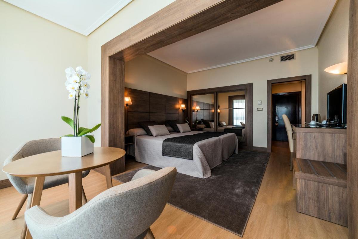 Una habitación de hotel con una cama, una mesa y sillas. en Eurostars Louxo Talaso, en Isla de la Toja