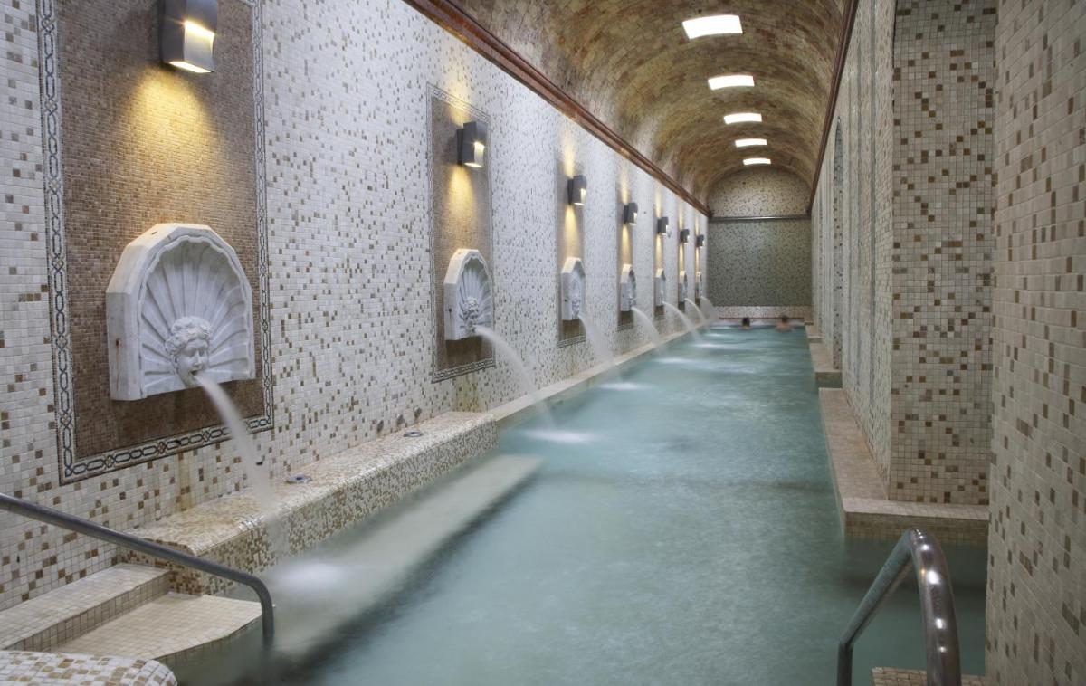 Un largo pasillo con urinarios en las paredes de un baño. en Hotel Parque Balneario Termas Pallares, en Alhama de Aragón