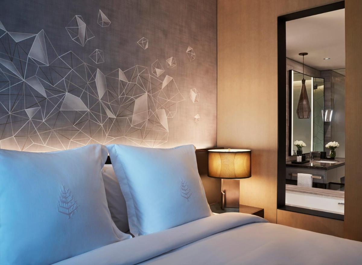 a bedroom with a bed with blue pillows and a mirror at Four Seasons Hotel Bengaluru at Embassy ONE in Bengaluru a bedroom with a bed with blue pillows and a mirror at Four Seasons Hotel Bengaluru at Embassy ONE in Bengaluru
