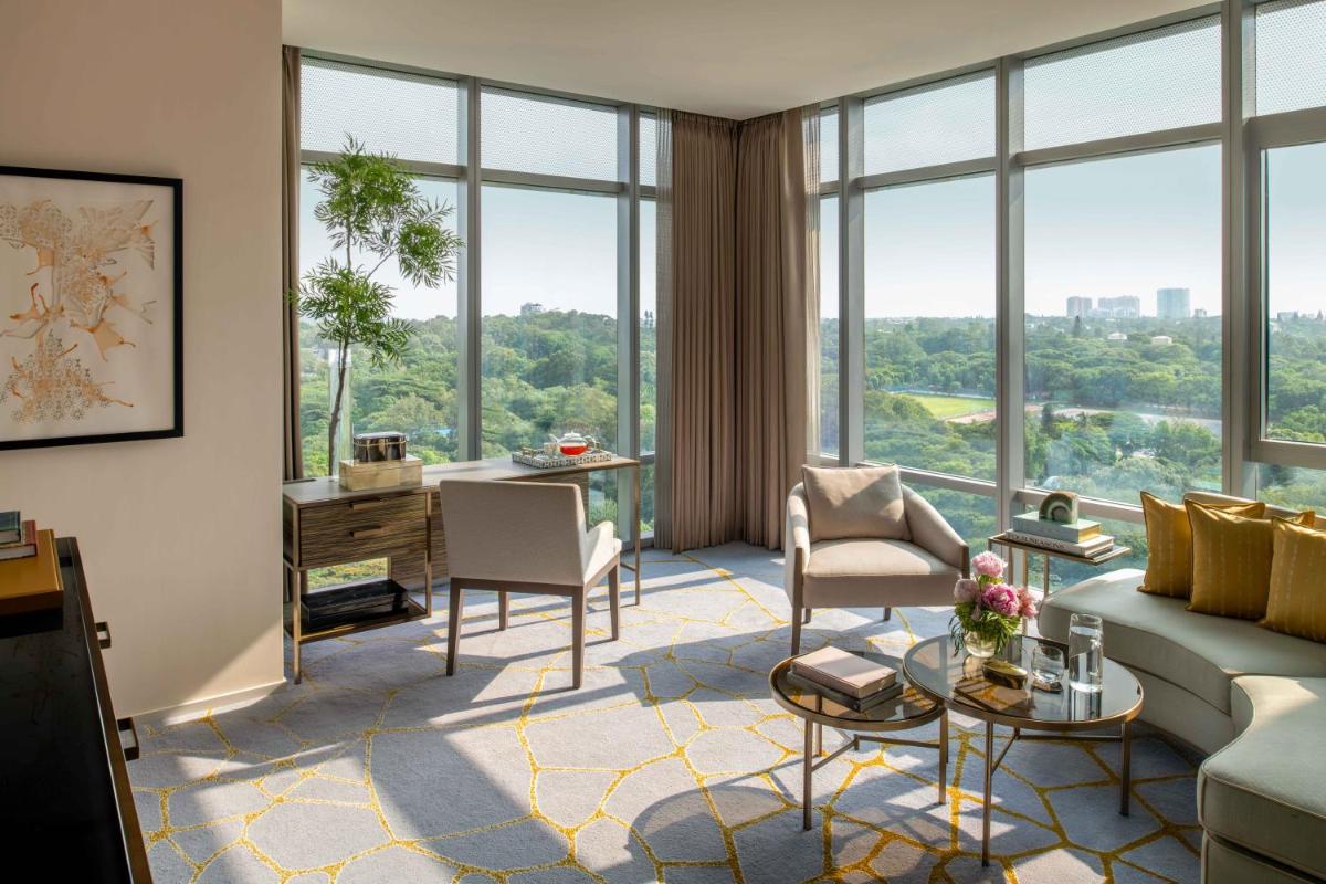 a living room with a couch and chairs and large windows at Four Seasons Hotel Bengaluru at Embassy ONE in Bengaluru a living room with a couch and chairs and large windows at Four Seasons Hotel Bengaluru at Embassy ONE in Bengaluru