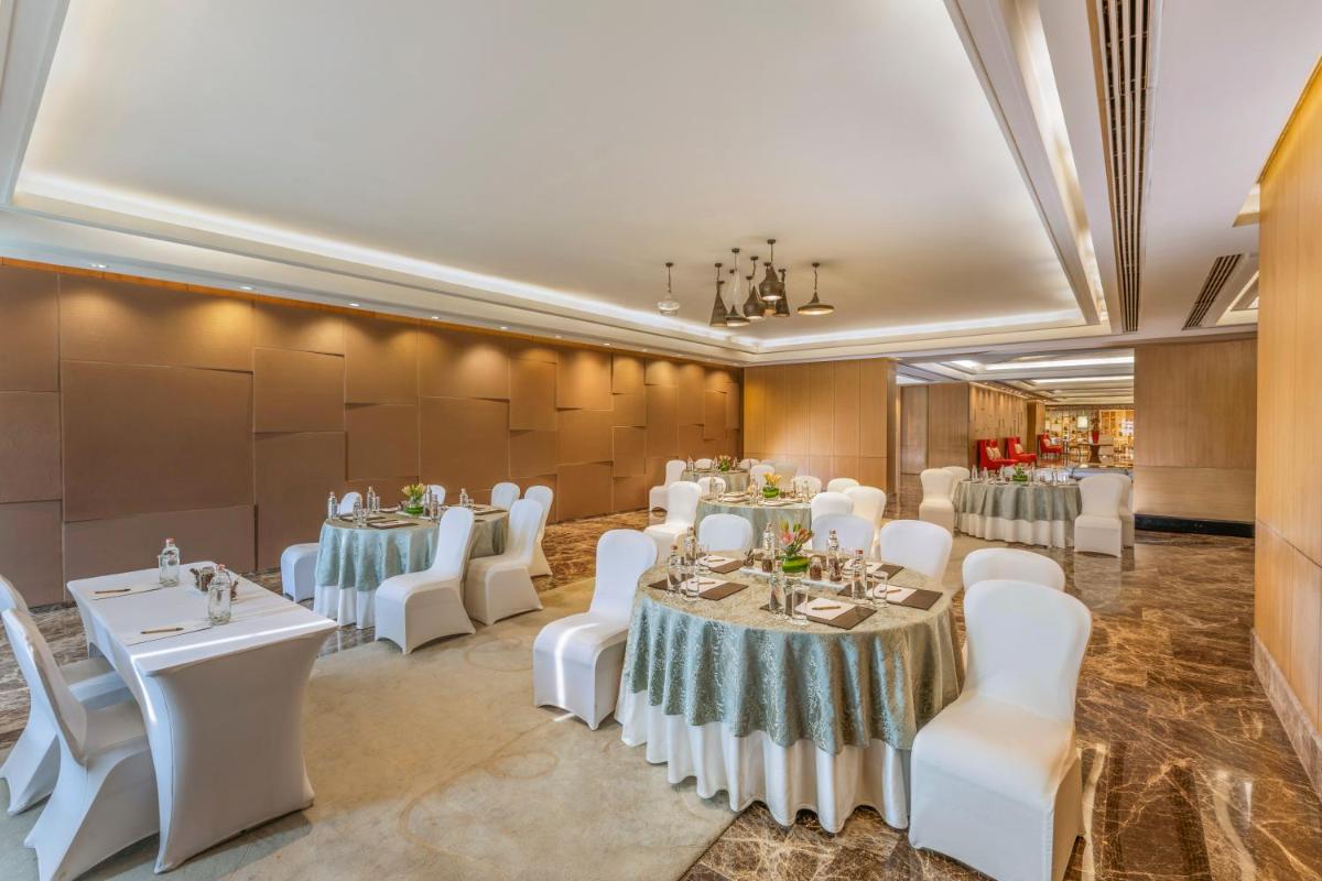 a banquet hall with white tables and white chairs at The Leela Ambience Convention Hotel Delhi in New Delhi