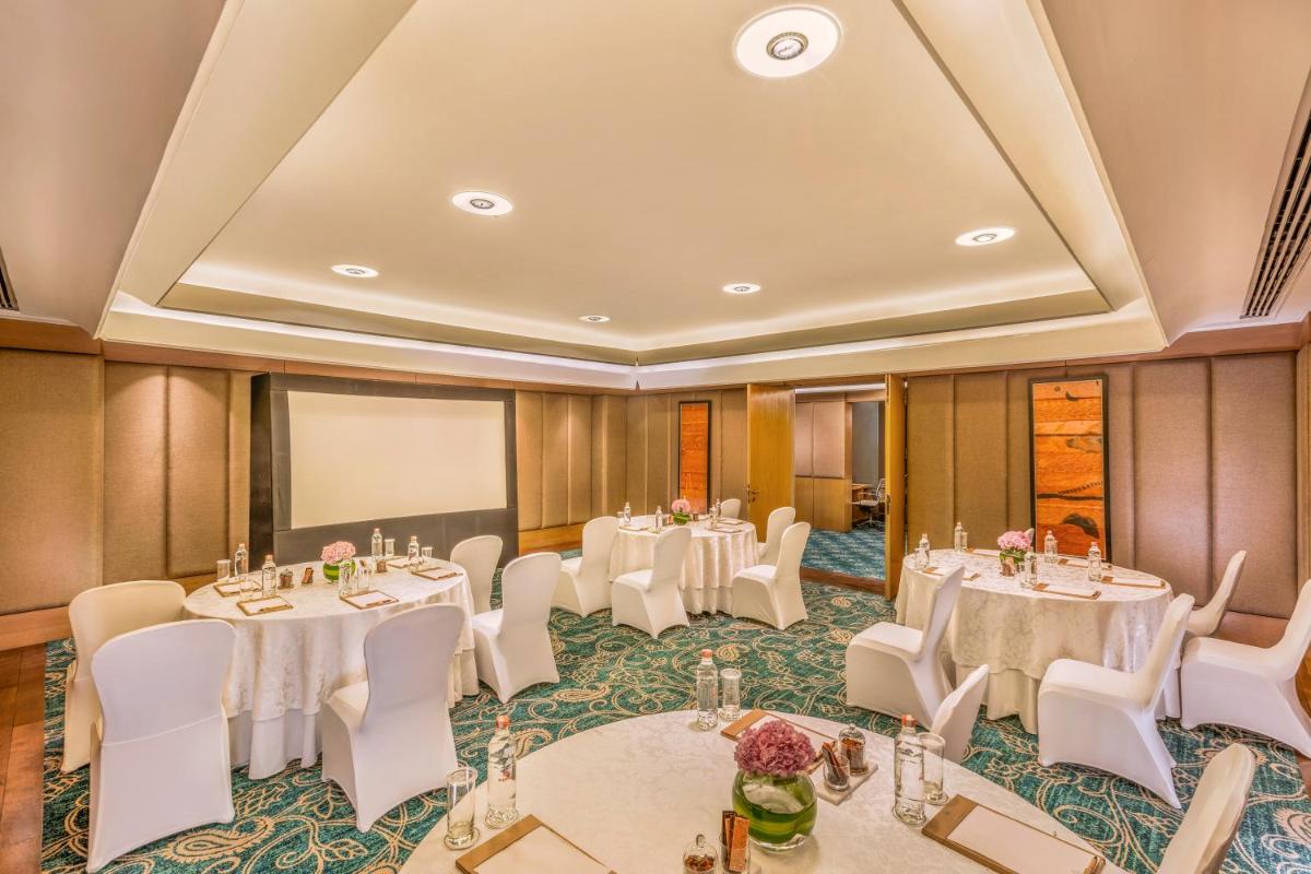 a conference room with tables and chairs and a projection screen at The Leela Ambience Convention Hotel Delhi in New Delhi
