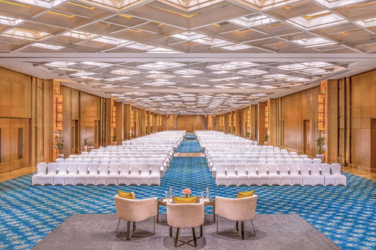 a large hall with rows of white chairs and tables at The Leela Ambience Convention Hotel Delhi in New Delhi